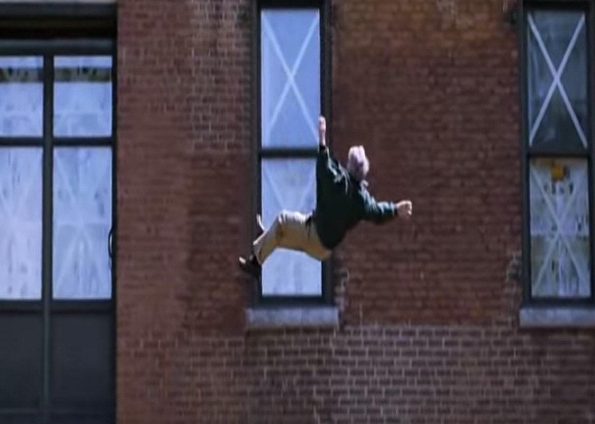 man falling from a building with the letter "x" appearing on the windows behind him