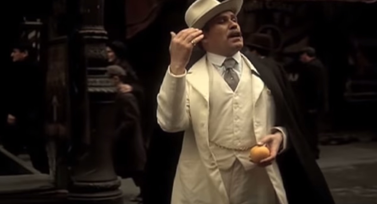 vito is walking down the street holding an orange