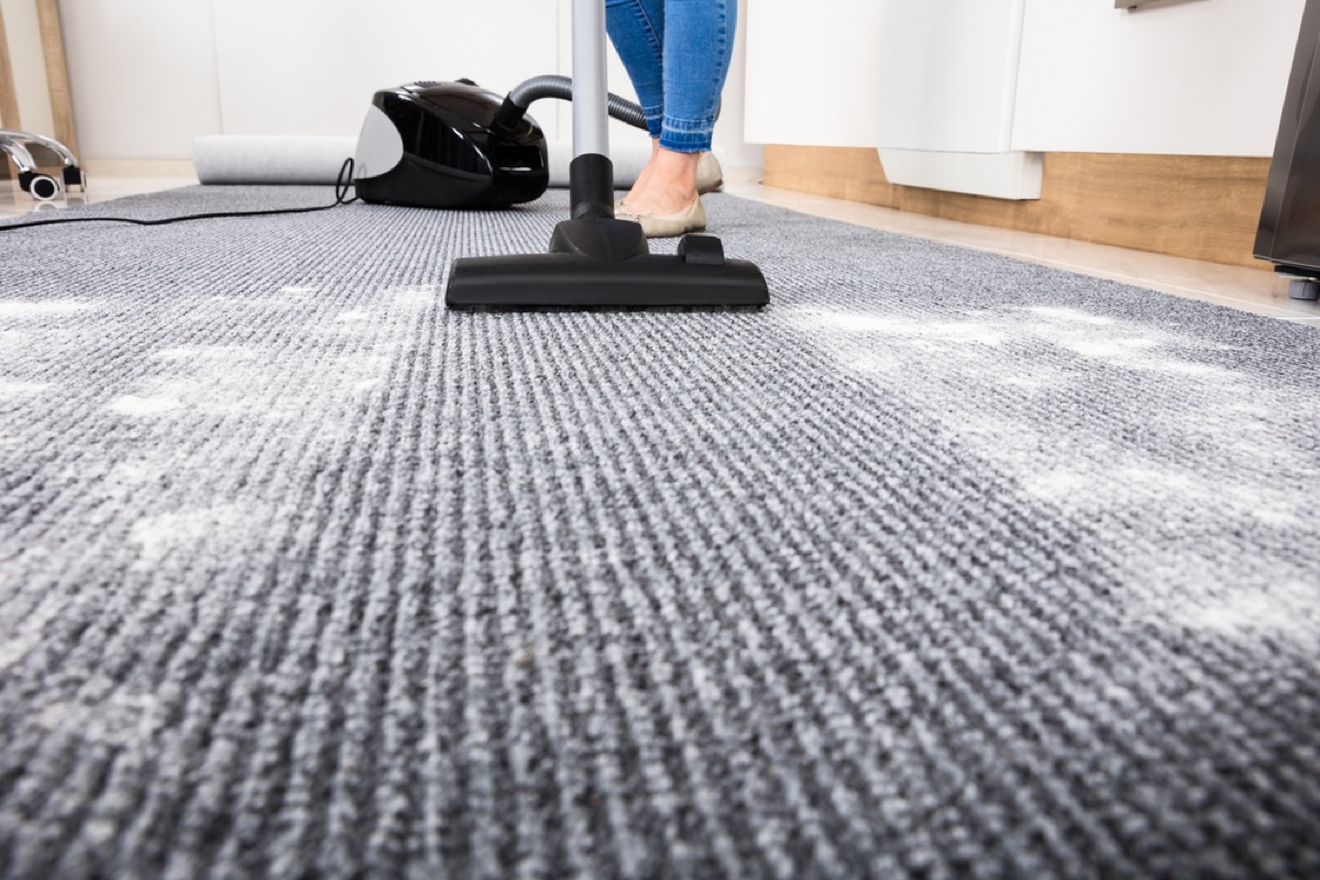 woman vacuuming up powder from carpet, easy home tips
