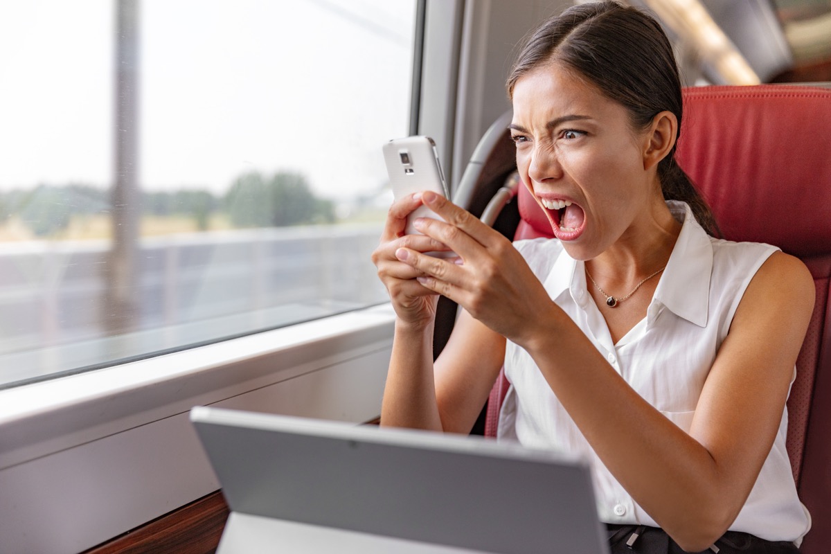 woman angrily yelling at the phone while on a laptop,