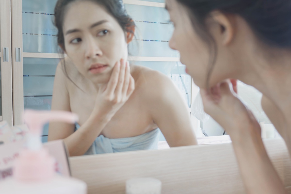 woman looking at her skin in the mirror, things husband should notice