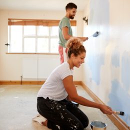 young couple painting wall with rollers