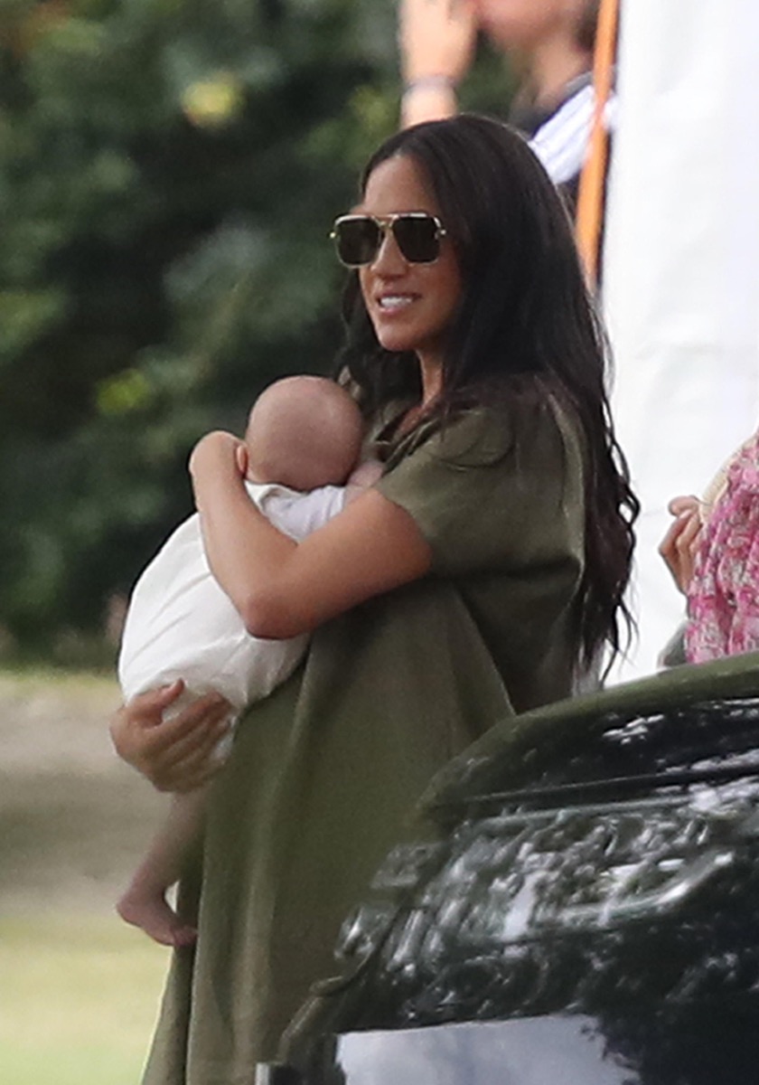 Meghan Markle holding her son Archie wearing green dress and aviator sunglasses