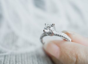 Closeup of woman's fingers holding engagement ring, postpone wedding