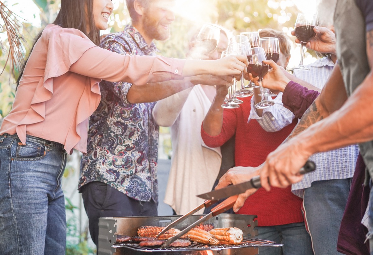 Friends cheers wine glasses at barbecue, husband came out at bisexual