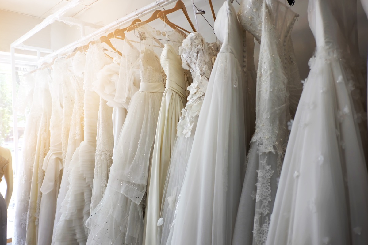 Wedding dresses hang on hangers in bridal store, postpone wedding