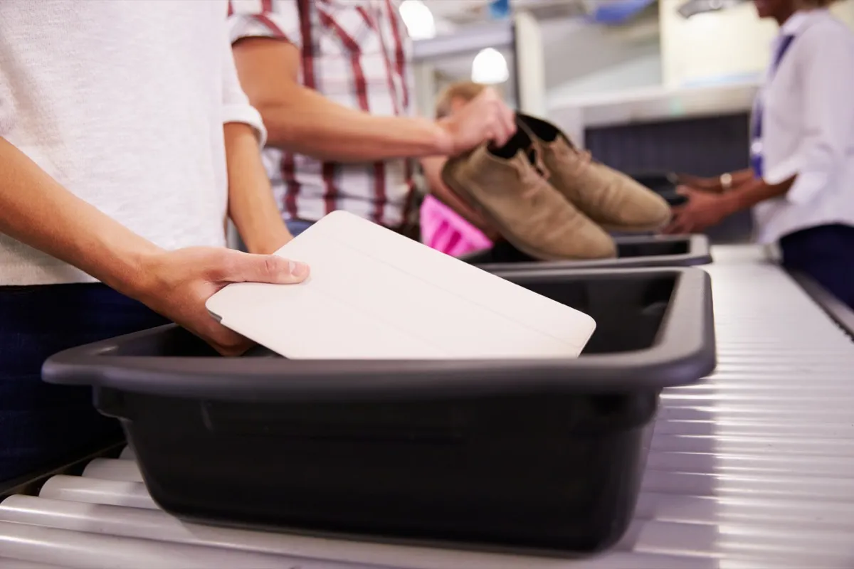 Oamenii își pun hainele în cutii de la aeroport