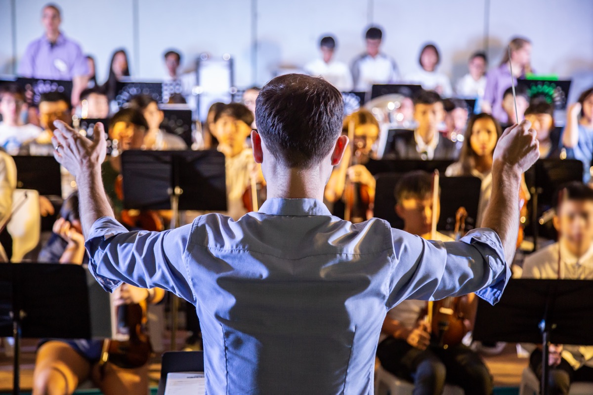 a conductor conducting a school orchestral band