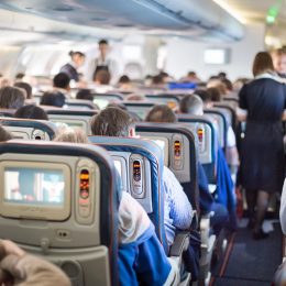 a flight attendant walks down the aisle of a crowded airplane