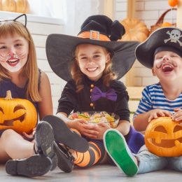 best halloween party games kids adults, kids sitting in costumes with pumpkins