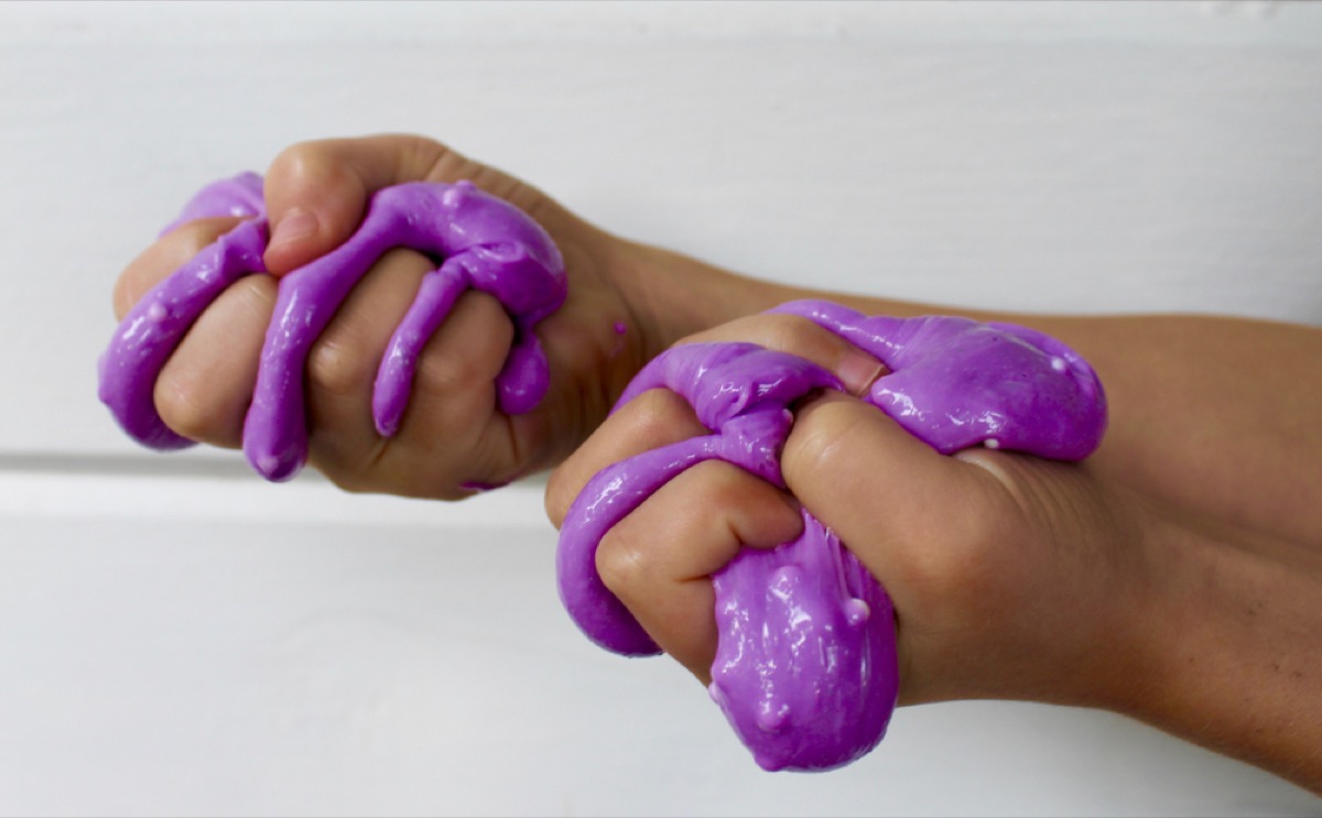 kid's hand squeezing purple slime, second uses for cleaning products