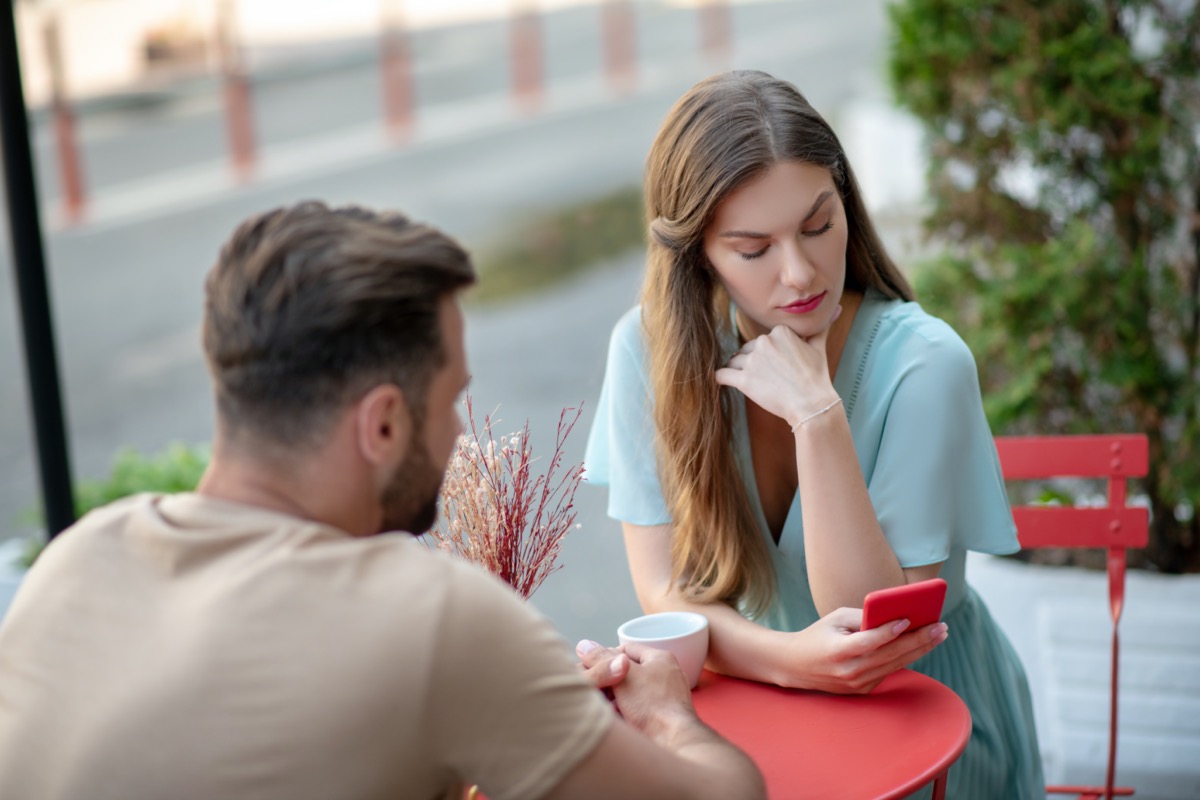 white woman and man talking outside while woman looks at phone