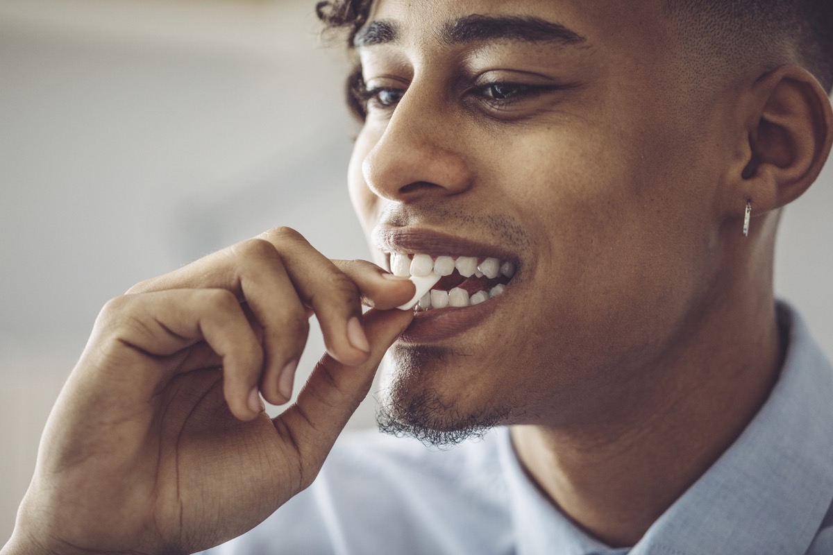Black man putting chewing gum in his mouth