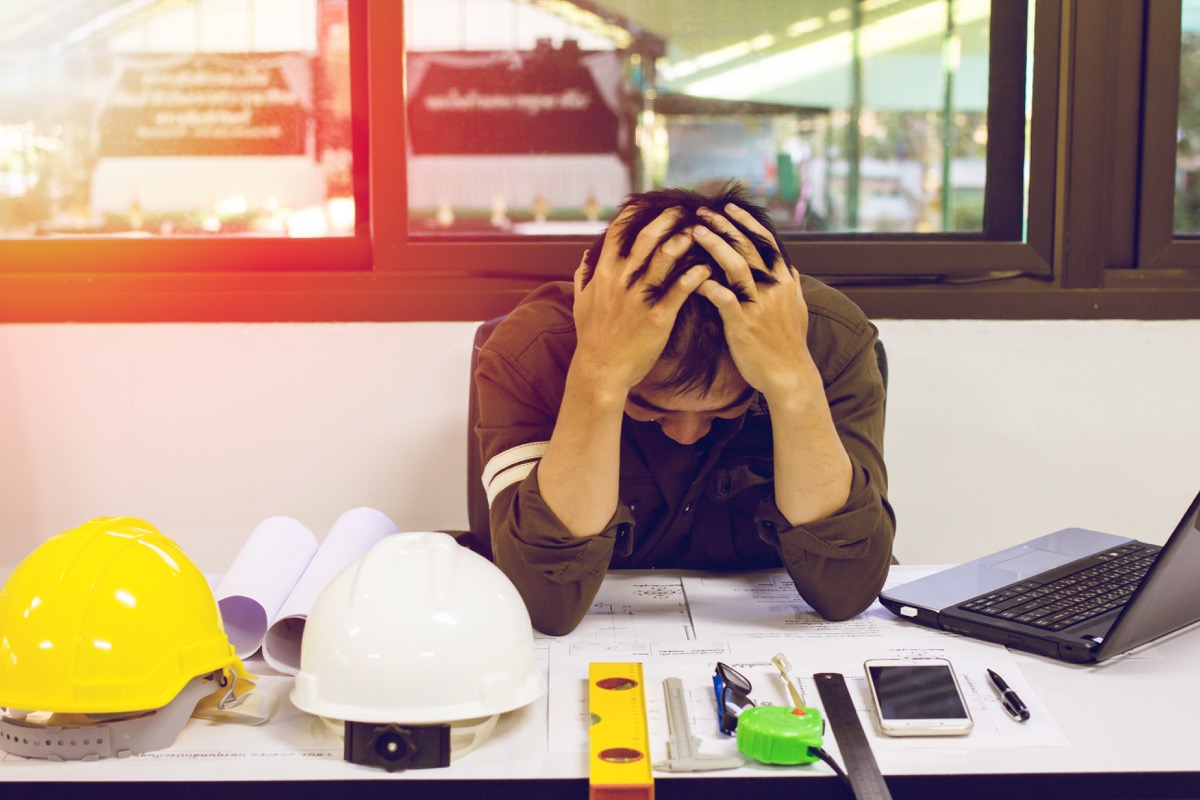 Man stressed at his desk at work potentially a construction manager
