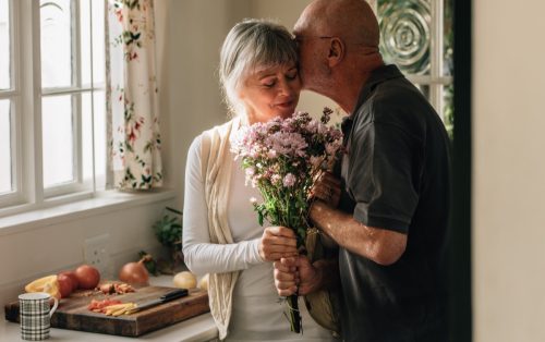 old man surprising his wife with flowers