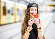 hipster woman applying red lipstick outdoors, summer beauty products