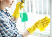 woman wiping window with cleaner, cleaning mistakes