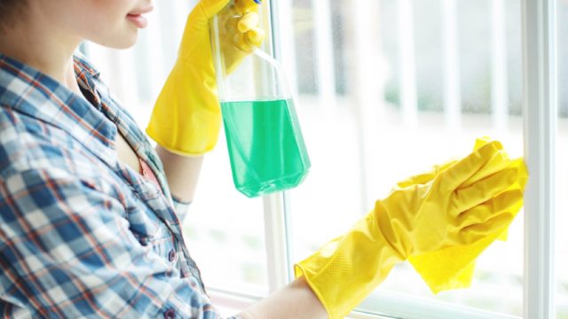 woman wiping window with cleaner, cleaning mistakes