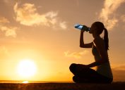 woman outdoors drinking water in front of sunset, cute water bottles
