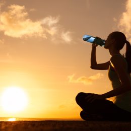 woman outdoors drinking water in front of sunset, cute water bottles