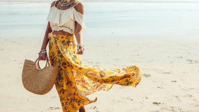 woman in yellow tote holding woven bag on the beach, luxury beach bags