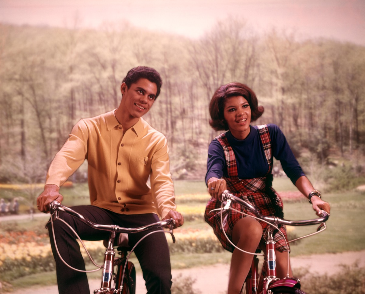 1960s AFRICAN AMERICAN TEENAGE BOY AND GIRL RIDING BICYCLES
