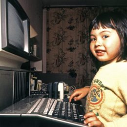 three year old Asian girl plays with a TI 99 4a home computer, 1986.