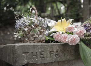 Flowers on grave that reads "The Family," story of widow at 40