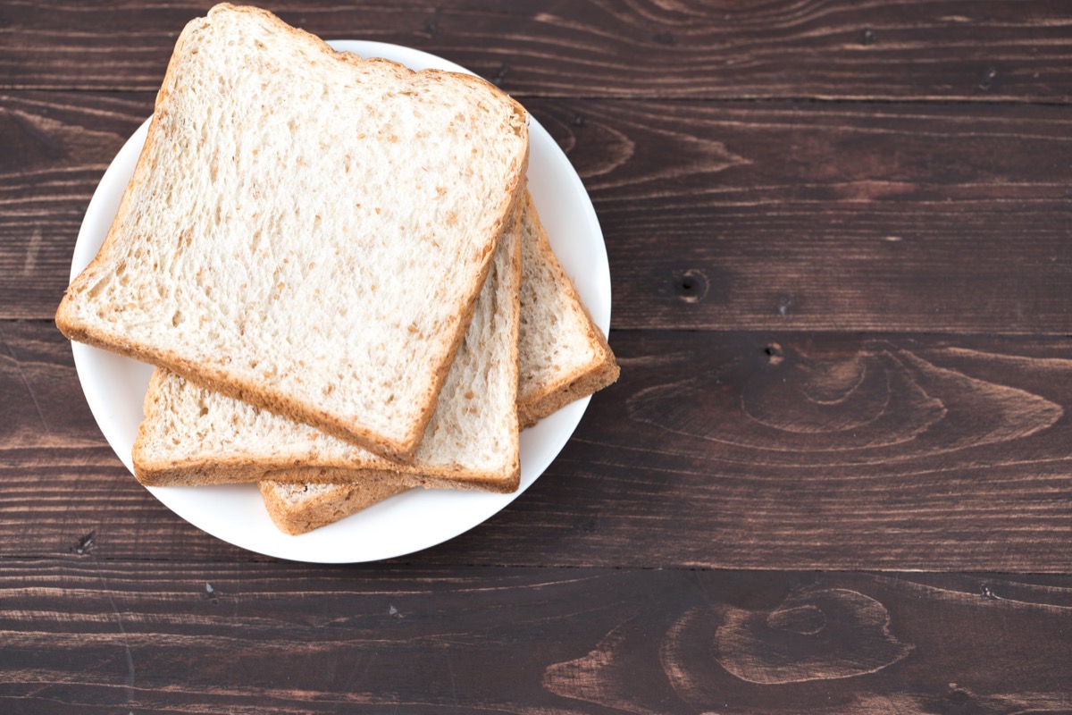 Three slices of white bread on white plate on wooden table, old-fashioned cleaning hacks