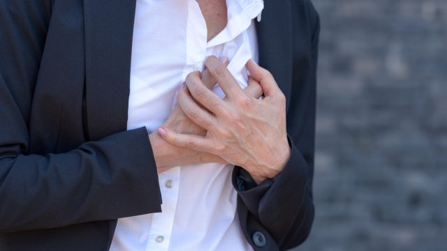 Business woman having a heart attack and grabbing her breast in a close up view