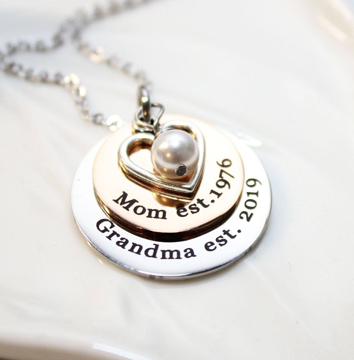 two engraved metal discs, a heart pendant, and a pearl on a silver chain, best gifts for grandparents