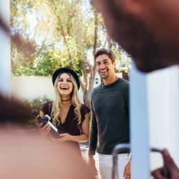 couple arriving at party with bottle of wine, housewarming gifts