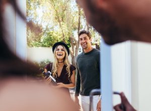 couple arriving at party with bottle of wine, housewarming gifts