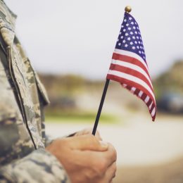 military man holding american flag - veterans day quotes
