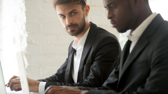 Jealous Male Coworker Looking at a Fellow Employee Things He Won't Admit