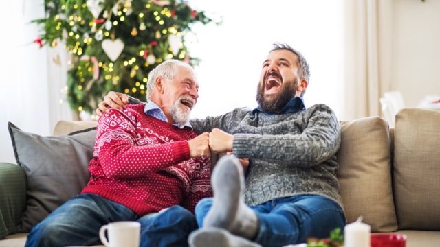Two men laughing on a couch during Christmas time