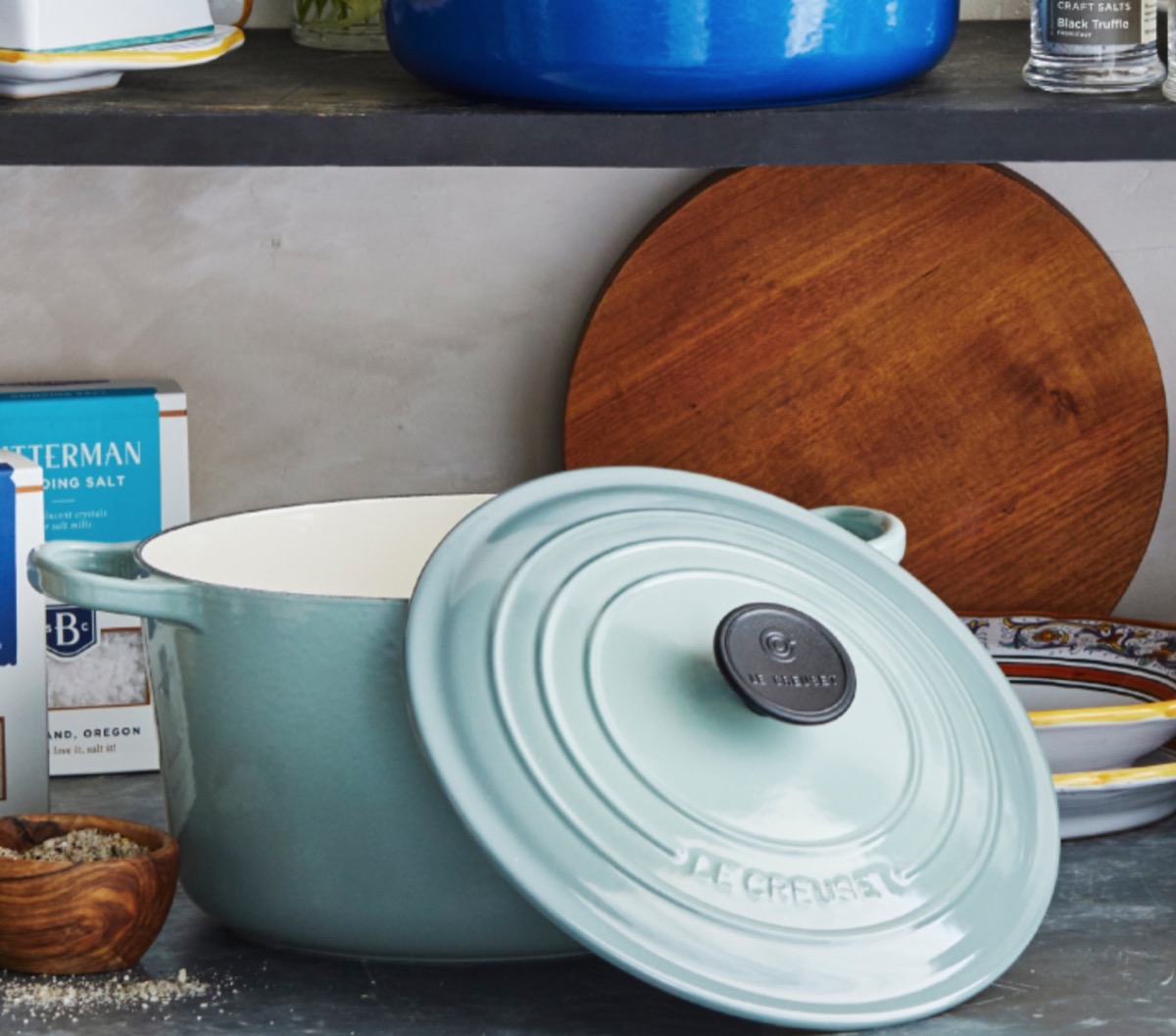 blue ceramic dutch oven on kitchen countertop with brown cutting board in background