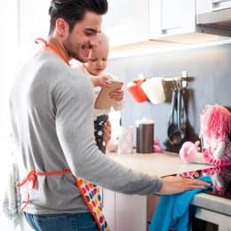 a father and his baby cleaning the kitchen counter