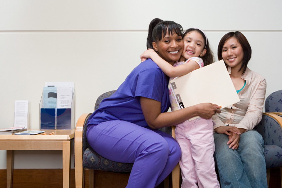 nurse hugging young girl while mother sits in chair next to them, school nurse secrets