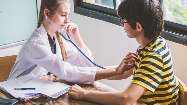 school nurse treating young male patient with stethoscope on his chest, school nurse secrets