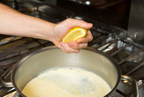 hand squeezing lemon into pan