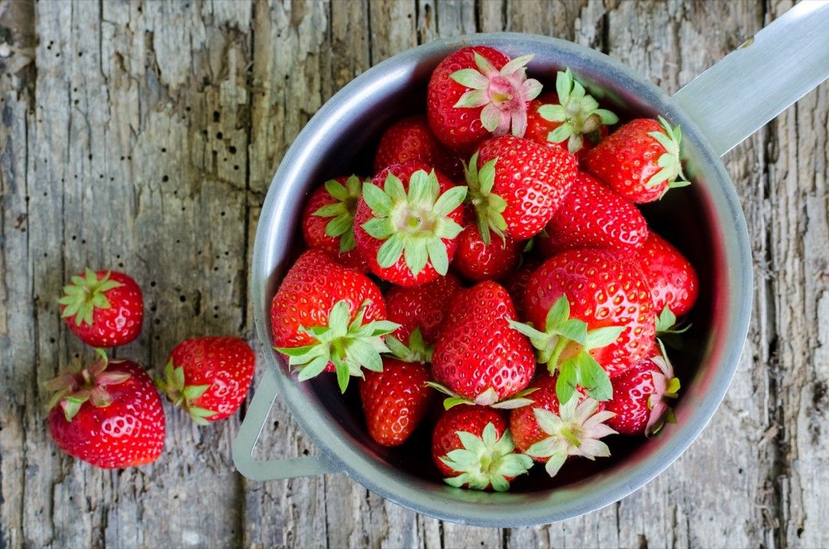 a cup of fresh strawberries on a wooden table, trademark failures