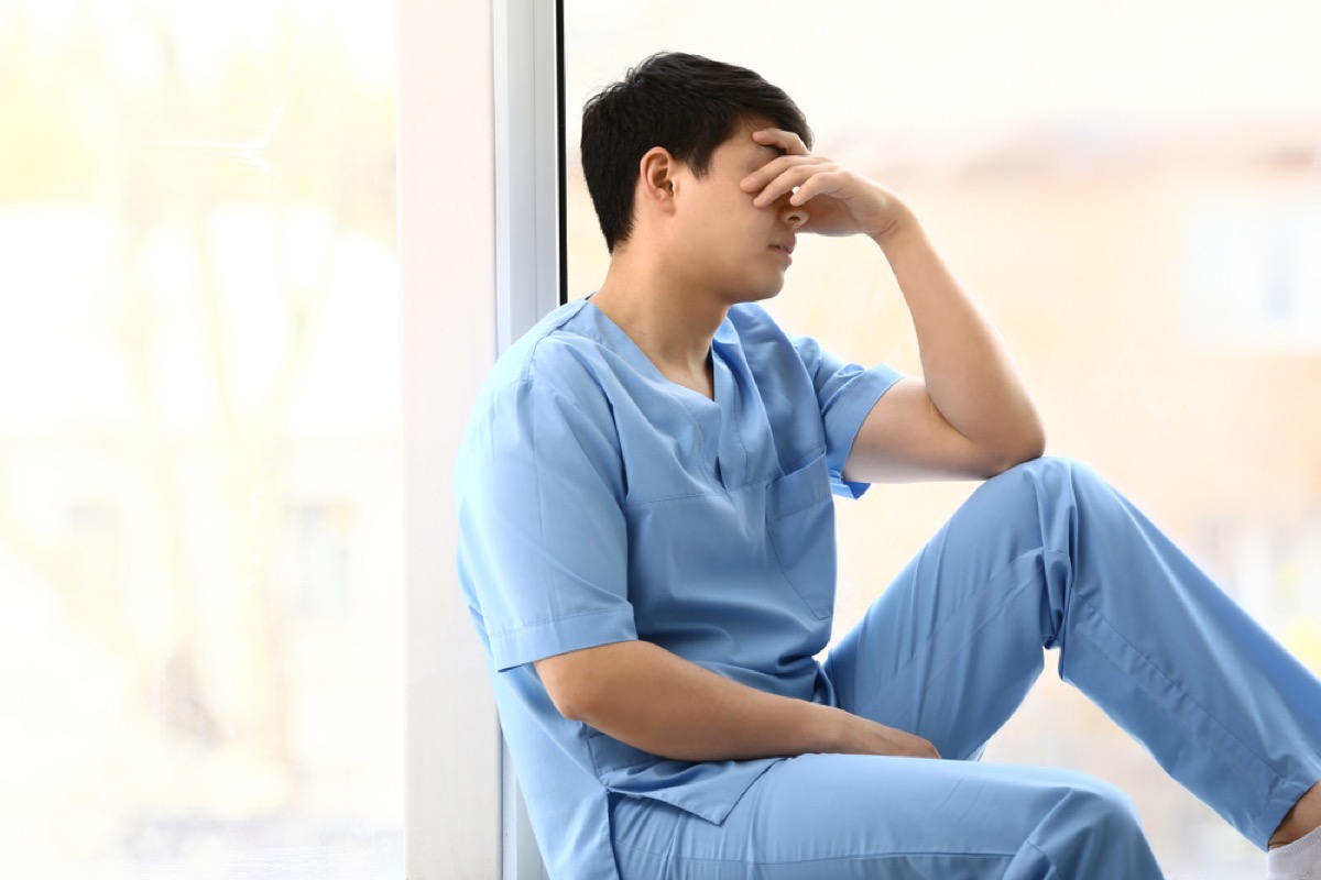 stressed out man in scrubs sitting in hallway, school nurse secrets