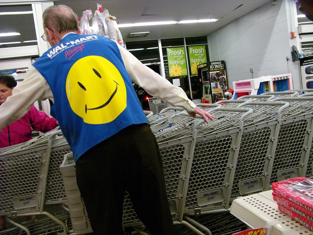 a walmart employee wearing a blue vest featuring a smiley face