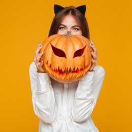 woman wearing cat ears and holding jack o'lantern,