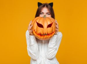 woman wearing cat ears and holding jack o'lantern,