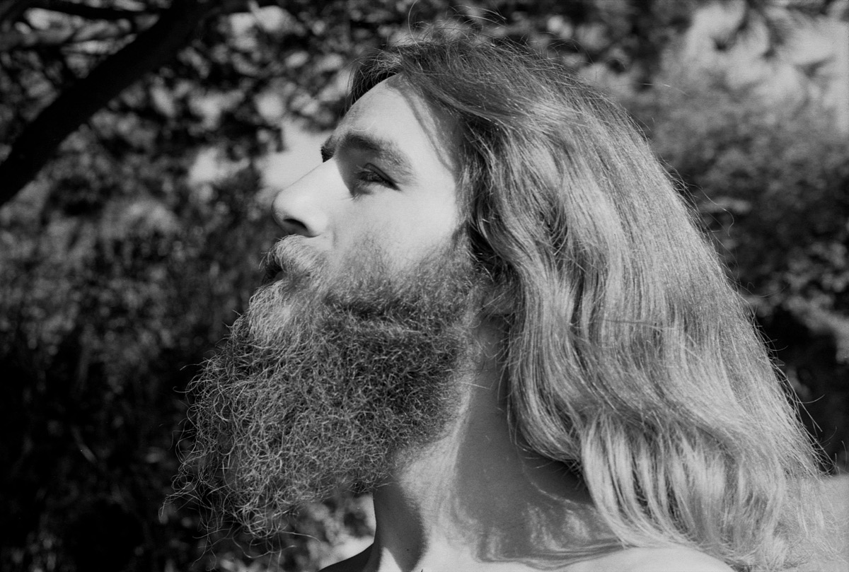Portrait of 1970s hippie man with beard and long hair being spiritual in Berkeley, California in the 1970s