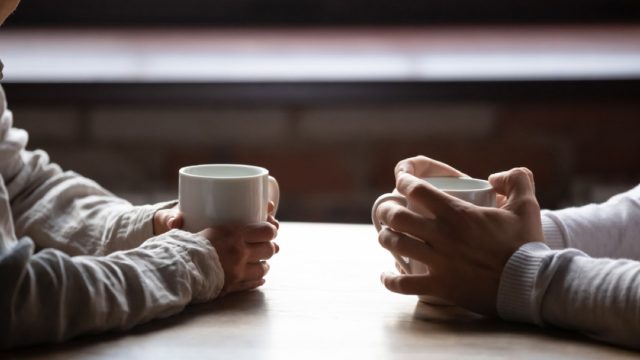 Closeup of couple's hands having coffee at table