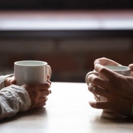 Closeup of couple's hands having coffee at table