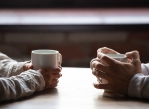 Closeup of couple's hands having coffee at table